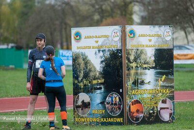 uczestnicy biegu z banerem partnera biegu w tle